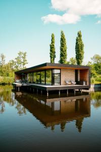 a house on a dock on a body of water at Haven Lake Village in Kortenhoef
