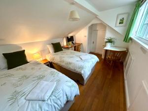 a bedroom with two beds and a desk and a window at Cotswolds Retreat in Tewkesbury