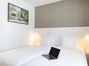 a laptop sitting on a bed in a hotel room at Mercure Strasbourg Centre Petite France in Strasbourg