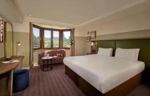 a hotel room with a large bed and a fireplace at Mount Royal Hotel Edinburgh by The Unlimited Collection in Edinburgh