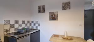 a kitchen with a sink and a stove with pictures on the wall at T1 rénové 24m2 Cosy Confort ! in Anzin +10 photos