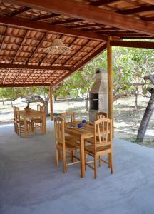 a wooden table and chairs under a pavilion with a fireplace at Suite Sol - Quarto e Banheiro com Ar Condicionado in Luis Correia