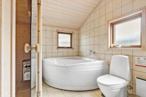ein Badezimmer mit einer weißen Badewanne und einem WC in der Unterkunft 8451 Knebel - Fyrrevej 9 in Knebel + 20 Fotos