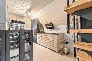 une cuisine avec des placards noirs et blancs et un escalier dans l'établissement 84109-8400-Birkevej-1, à Øksenmølle