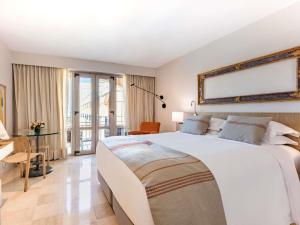 a bedroom with a large white bed and a desk at Sofitel Legend Santa Clara Cartagena in Cartagena de Indias