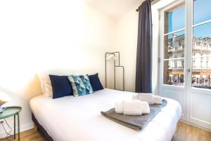 a white bed in a room with a window at Appartements - Bordeaux Centre Gare in Bordeaux
