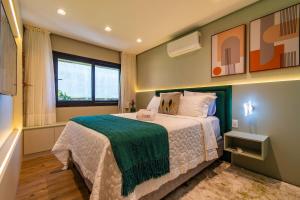 ein Schlafzimmer mit einem Bett mit einer grünen Decke darauf in der Unterkunft Rosa Edificio Residencial Storia in Gramado