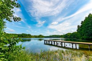 a bridge over a river with trees and clouds in the sky at Jugendbegegnungsstätte Am Kutzow-See Plöwen in Plöwen +2 photos