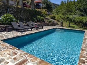 a swimming pool with two chairs and a table in a yard at O Celeiro in Vale da Vide