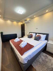 a bedroom with a large bed with towels on it at Local-Lux Apartman 3 szoba, privát parkoló in Kecskemét