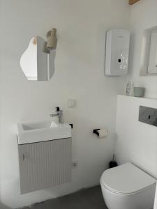 a white bathroom with a toilet and a sink at Modernes Studio mit en-Suite Bad & bester Anbindung in Düsseldorf