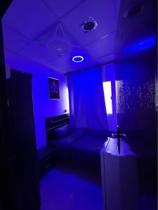 シャルジャにあるLuxury single room in sharjahのベッドと青いライト付きのダークルーム
