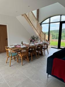 a dining room with a wooden table and chairs at Threshing Barn- Modern 5 Bed, 10 person, Barn Conversion in a Rural Location with Great Access in Silkstone