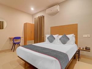 a bedroom with a large bed and a blue chair at Townhouse White Ridge KPHB OPP JNTU in Hyderabad