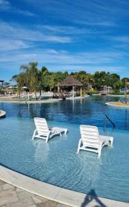 two white chairs in a pool of water at Iloa resort AP luxo in Barra de São Miguel