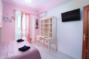 a bedroom with pink walls and a bed and a desk at Appartamento Le Palme Tra Taormina e Catania in Linera