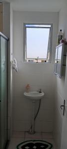 a white bathroom with a sink and a window at Aconchego in Marituba