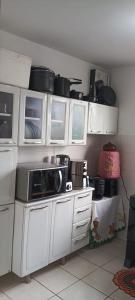 a kitchen with white cabinets and a microwave at Aconchego in Marituba +12 photos