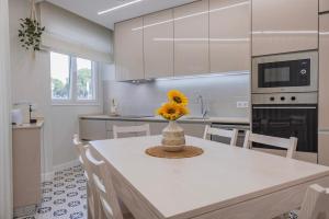 a kitchen with a table with a vase of flowers on it at Modern 2BR Apt with Patio and AC in Lisbon