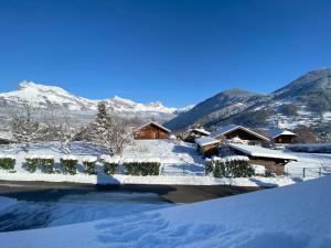 een huis bedekt met sneeuw met bergen op de achtergrond bij Chalet Morets in Saint-Gervais-les-Bains