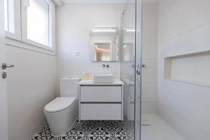a white bathroom with a toilet and a glass shower at Modern 2BR Apt with Patio and AC in Lisbon