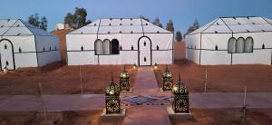 メルズーガにあるMerzouga Marvelous Campの砂漠にある2つのモスクとその前に灯りがある