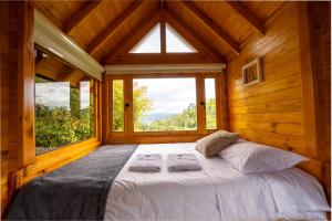 a bed in a wooden room with a large window at Cabaña de Pino Escapada Natural a 7 Min in Chiquinquirá