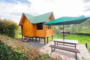 a small tree house with a picnic table and an umbrella at Cabaña de Pino Escapada Natural a 7 Min in Chiquinquirá