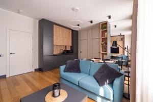 a living room with a blue couch and a kitchen at Premium One Bedroom Apartment Dzintari Beach & Park in Jūrmala