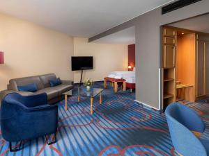 a hotel room with a couch and a bed at Mercure Hotel Berlin Tempelhof in Berlin