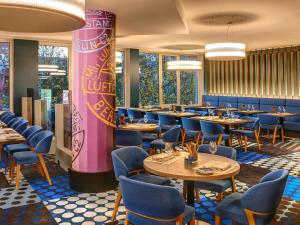 a dining room with tables and blue chairs at Mercure Hotel Berlin Tempelhof in Berlin