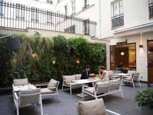 two people are sitting at tables in a restaurant at Mercure Paris Opera Garnier Hôtel & Spa in Paris
