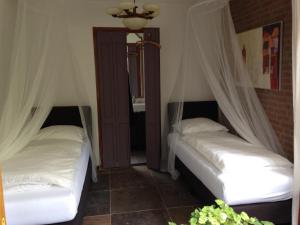 twee bedden in een kamer met witte lakens en gordijnen bij Hofje7 in Groesbeek