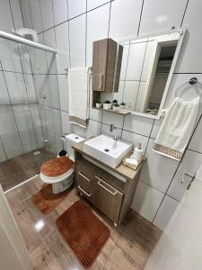 a bathroom with a sink and a toilet and a mirror at Della Giustina Residence Comforto Aparthotel - Aconchegante, Lindo, Moderno, Renovado entre Abba Pai Church e Centro in Criciúma +46 photos
