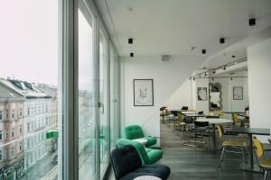 a room with chairs and tables and a large window at Hotel BEE GREEN Schönbrunn in Vienna