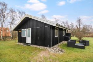 a black house with white doors on a grass field at 20125-Samso-Spaetmejsevej-2 in Nordby