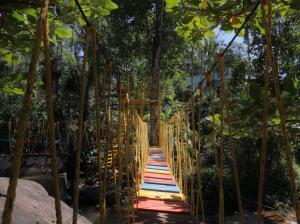 a suspension bridge in a park with trees at Nature Stay - Private Water Stream and a Pool in Aldūr