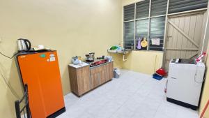 a kitchen with an orange refrigerator and a stove at Home Stay Lembah Bujang in Bedung