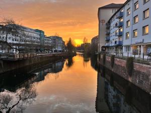 a river in a city at sunset with buildings at Goldstadt Apartments in Pforzheim