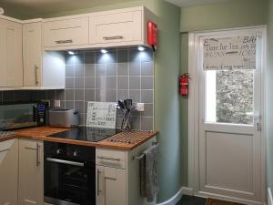 a kitchen with white cabinets and a black stove top oven at Seascape - St Catherine's Court in Fowey