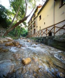 a river in front of a building with a bridge at Historic Boutique Hotel Maccarunera in Campagna