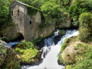 un fiume con un edificio in pietra accanto a una cascata di Maison des Cévennes - Refuge ad Arphy