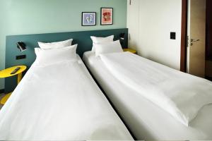 two beds sitting next to each other in a room at Garner Hotel Osnabrück by IHG in Osnabrück +123 photos