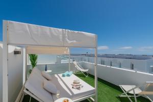 a balcony with a white couch and chairs on a roof at Villa Serena Blanca by Villalia Luxury Oasis & Private Pool in Playa Blanca