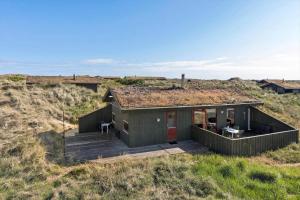 a small house with a grass roof on a beach at TV1532-Skagen-Solbakken-55 in Skagen