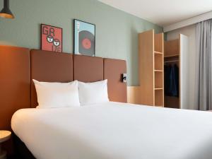 a bedroom with a large bed with white sheets at ibis Paris Gare de Lyon Ledru Rollin in Paris