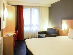 a hotel room with a bed and a chair and a window at ibis Paris Gare de Lyon Ledru Rollin in Paris