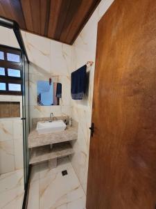ein Badezimmer mit Waschbecken und Spiegel in der Unterkunft Casa de condomínio 900m da Praia de Boiçucanga in São Sebastião