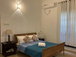 a bedroom with a bed with a blue comforter at Railside House in Seeduwa +2 photos
