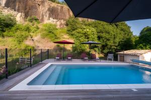 a swimming pool with chairs and umbrellas next to it at La Ferme De Mon Grand-père in Saint-Pons